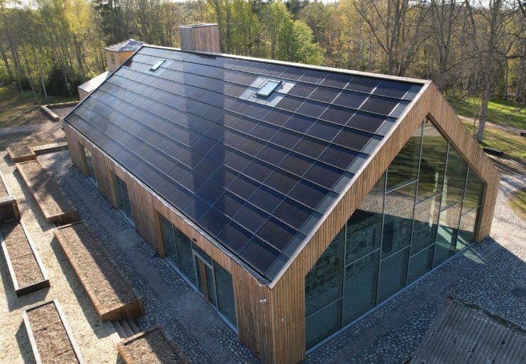 Aerial view of a timber community building with a full Quad+ solar roof running edge to edge